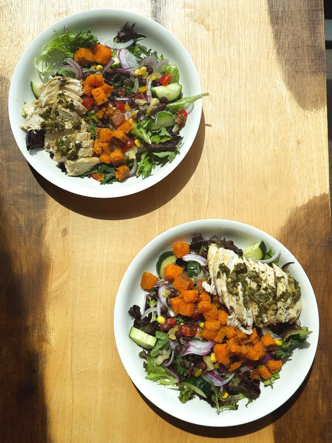 Two fresh salad bowls on a wooden table